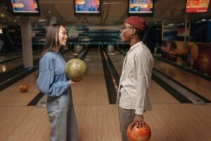 a boy and girl holding balls near a bowling lane