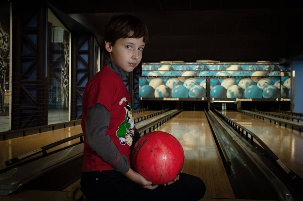 boy holding a bowling ball beside the lane