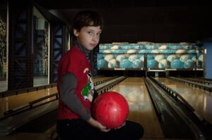 boy holding a bowling ball beside the lane