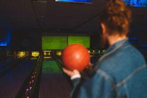 man holding a ball beside bowling lane