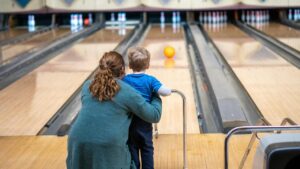 toddler practicing bowling with mom