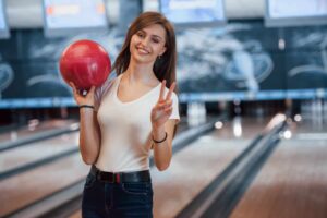 woman in casual clothes holding red bowling ball in the club