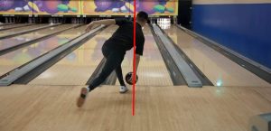 a bowler is releasing a bowling ball